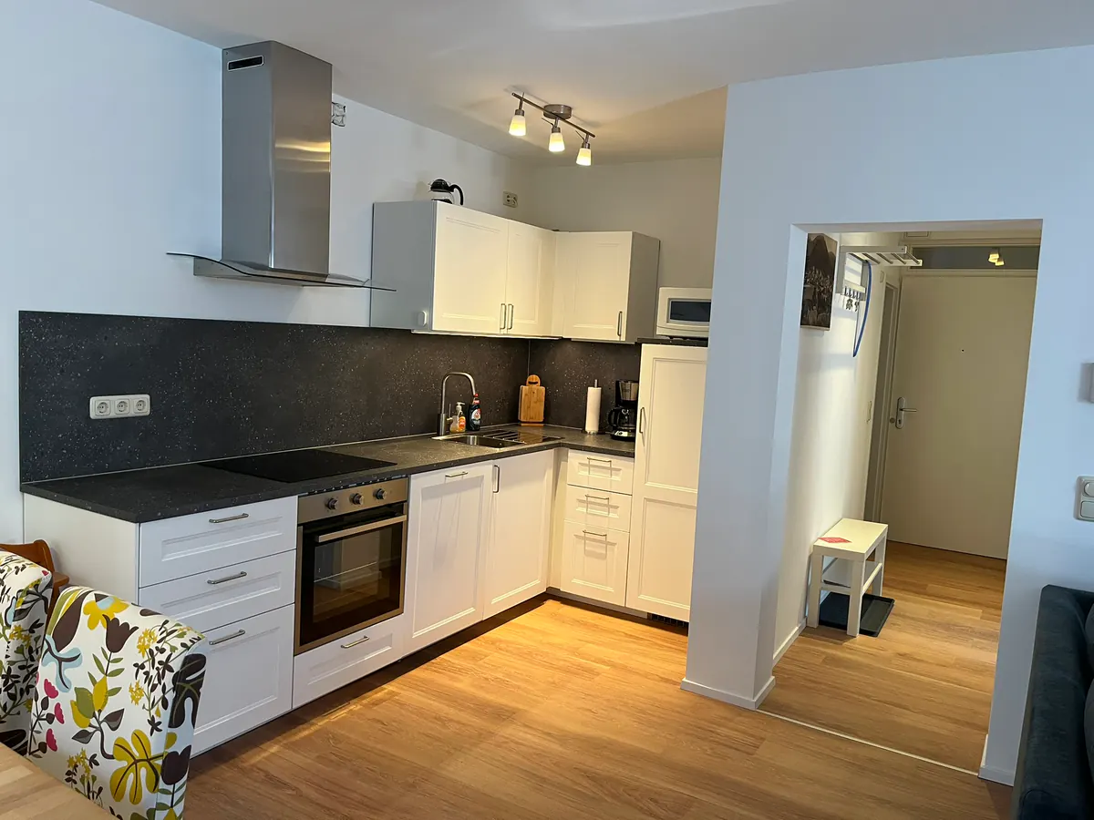 Kitchen with white units and dark worktop