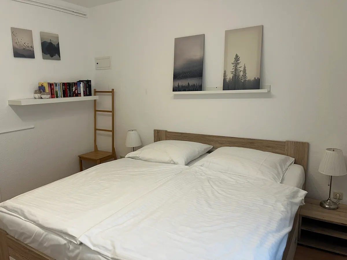 Schlafzimmer mit Doppelbett, Nachttischlampen und Regal