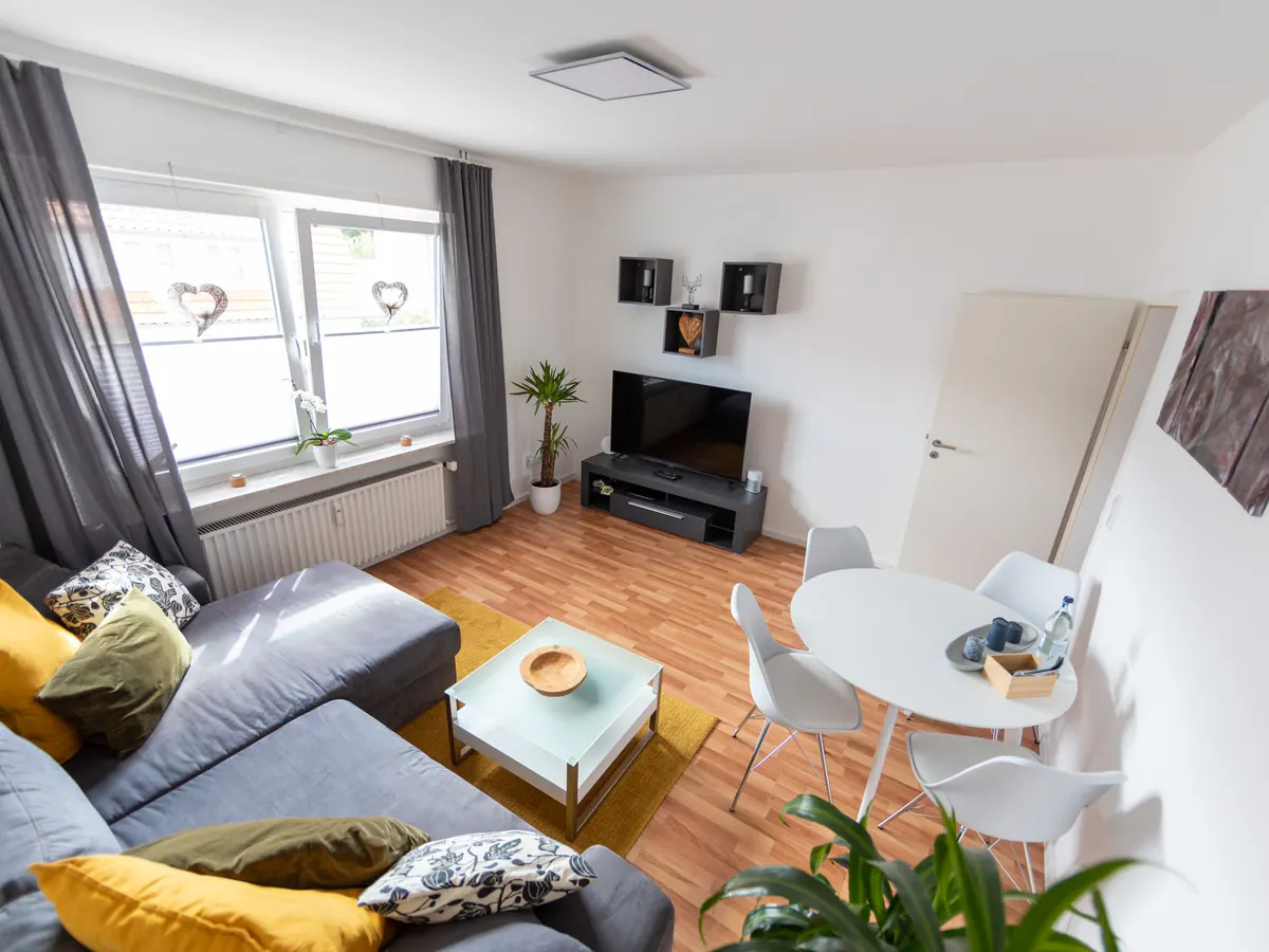 Heller Wohnraum der FeWO Martin 3 mit grauem Sofa und Essplatz