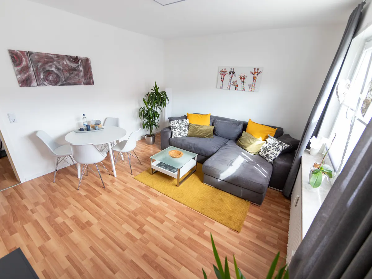 Wohnbereich mit Ecksofa und senfgelbem Teppich